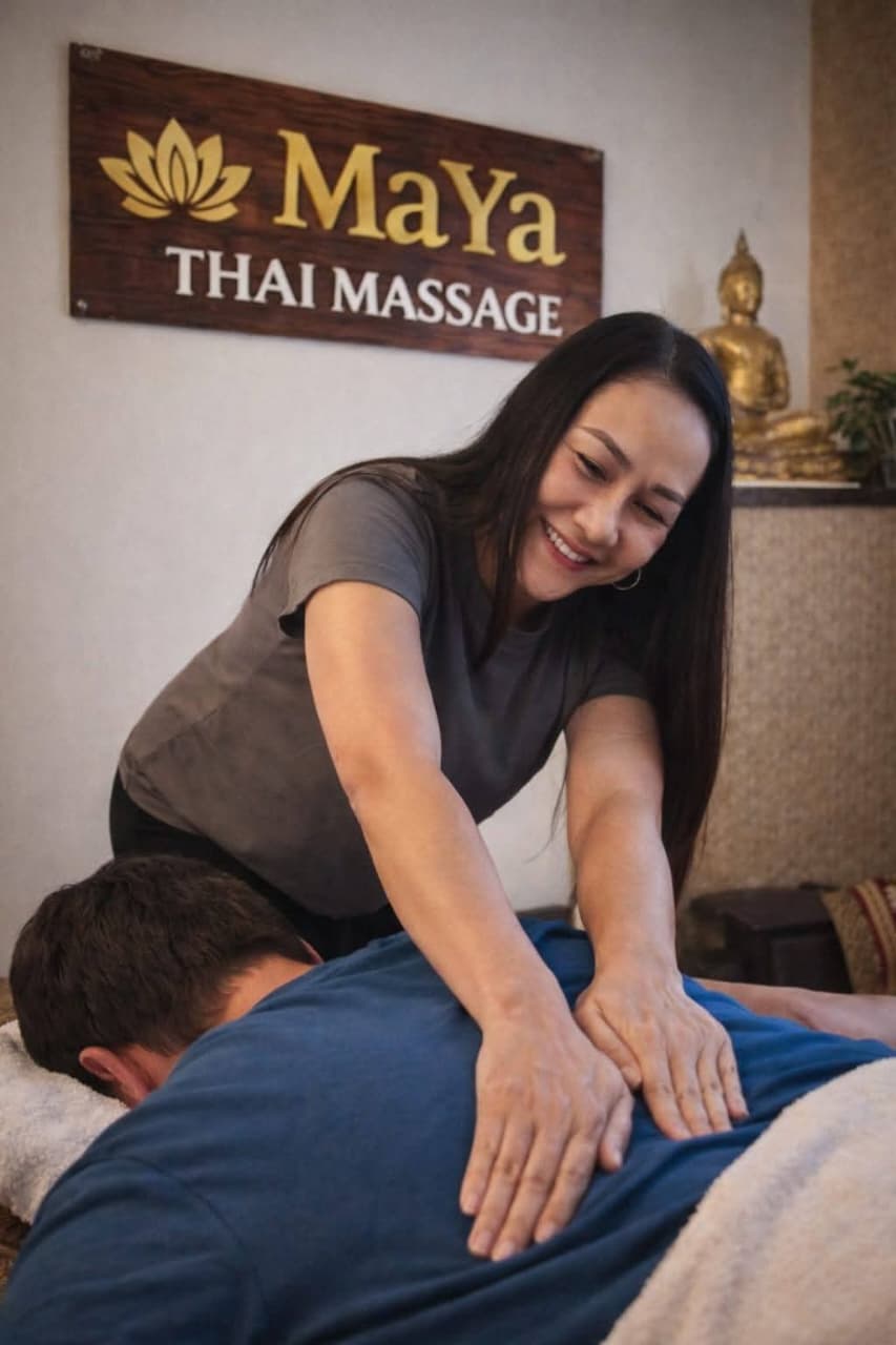 Maya Thai Massage therapist working on a guest beneath the Maya Thai Massage sign