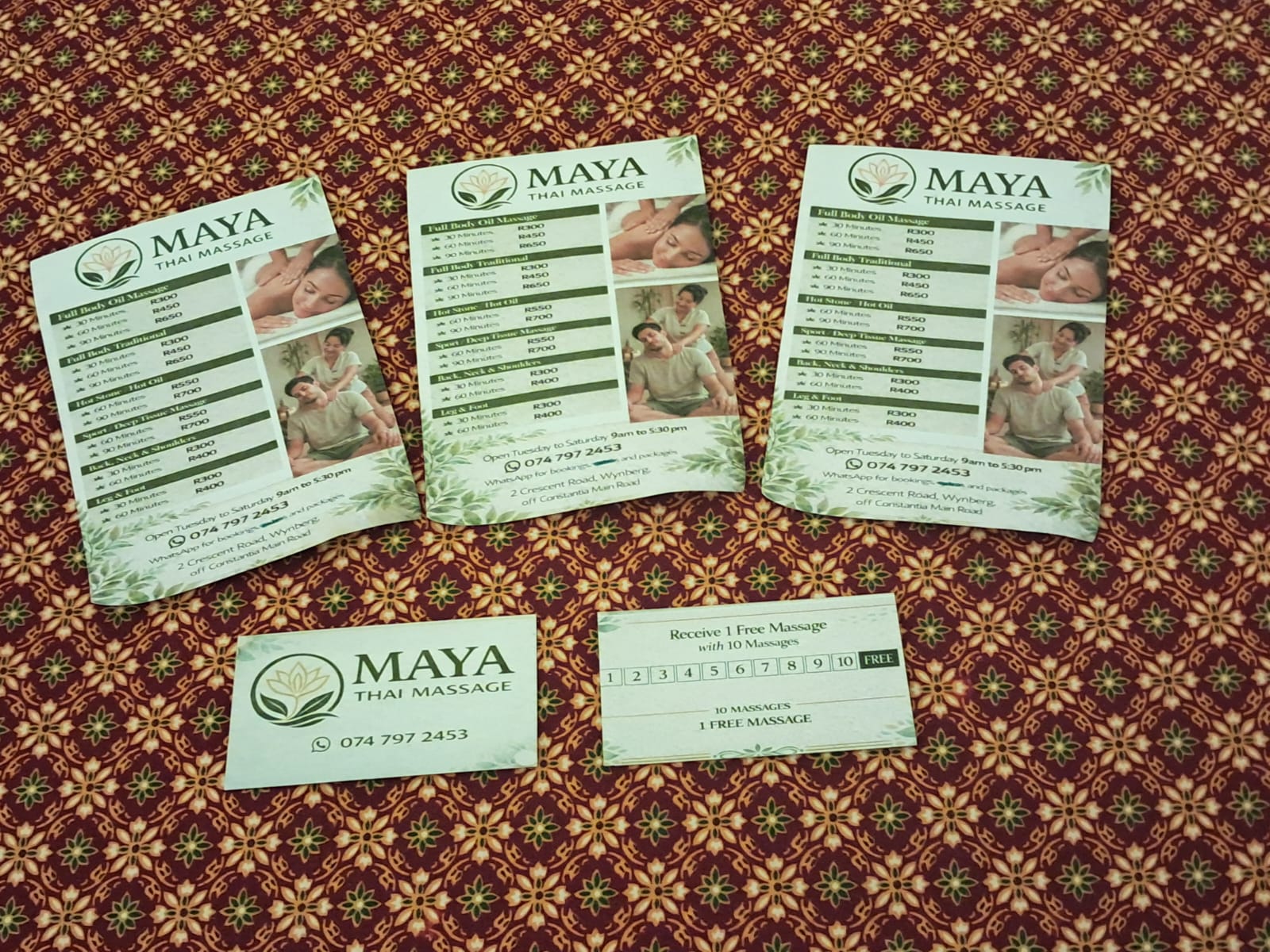 Maya Thai Massage price list flyers and loyalty card on a patterned Thai mat